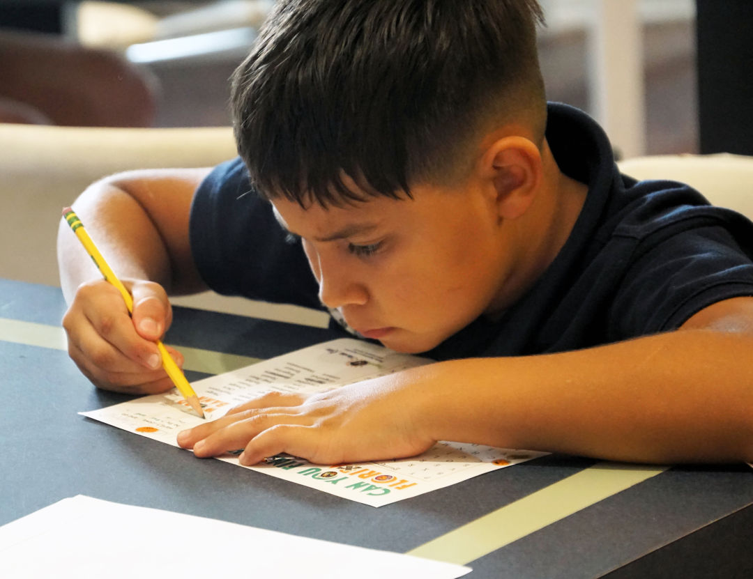 Carlos works his way through a workbook page.