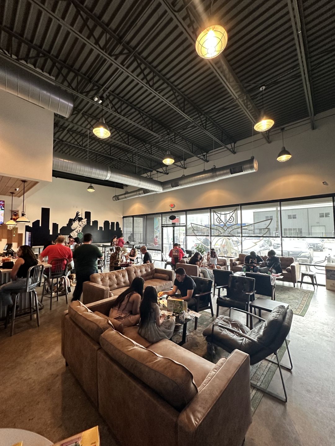 A group of people put together a lego set in a brewery with high ceilings.