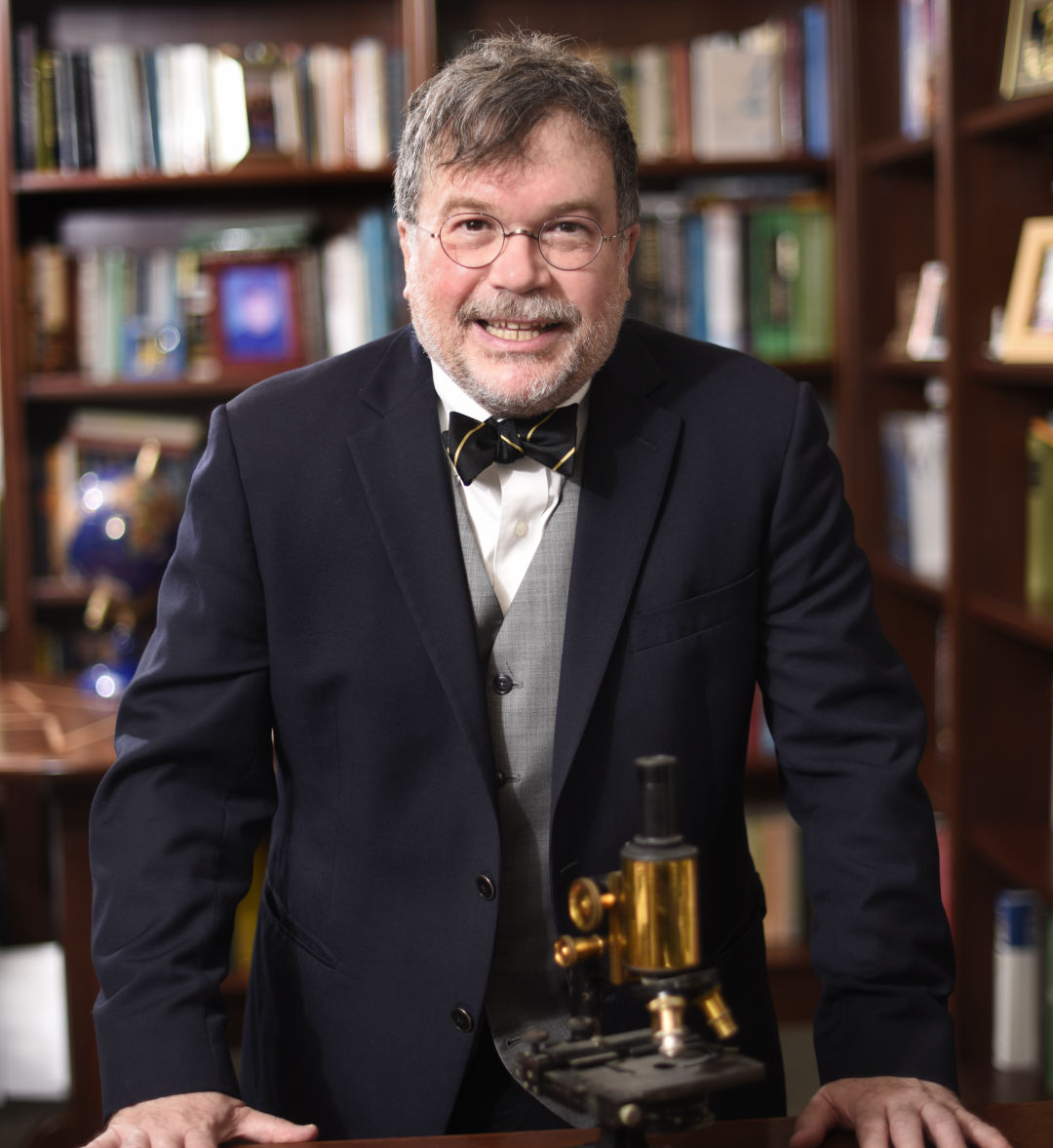 Dr. Peter Hotez stands in front of a microscope.