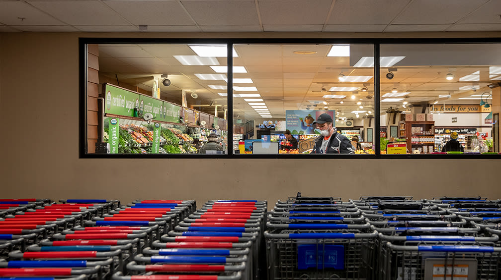 A person wearing a mask that does not cover his nose shops for produce inside a grocery store