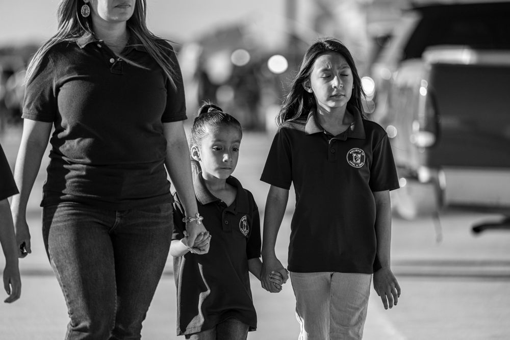 Family walking to attend a vigil at Uvalde County Fairplex.