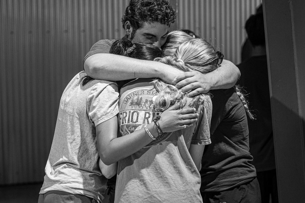 A family embracing in the hallway of the Uvalde County Fairplex after the vigil