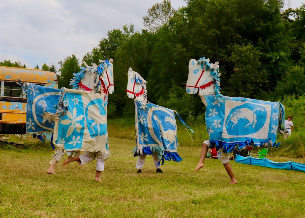 People dressed in playful full-body blue horse puppets.