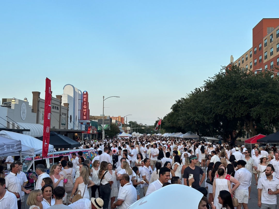 A large group of people in white outfits standing outside an old theater