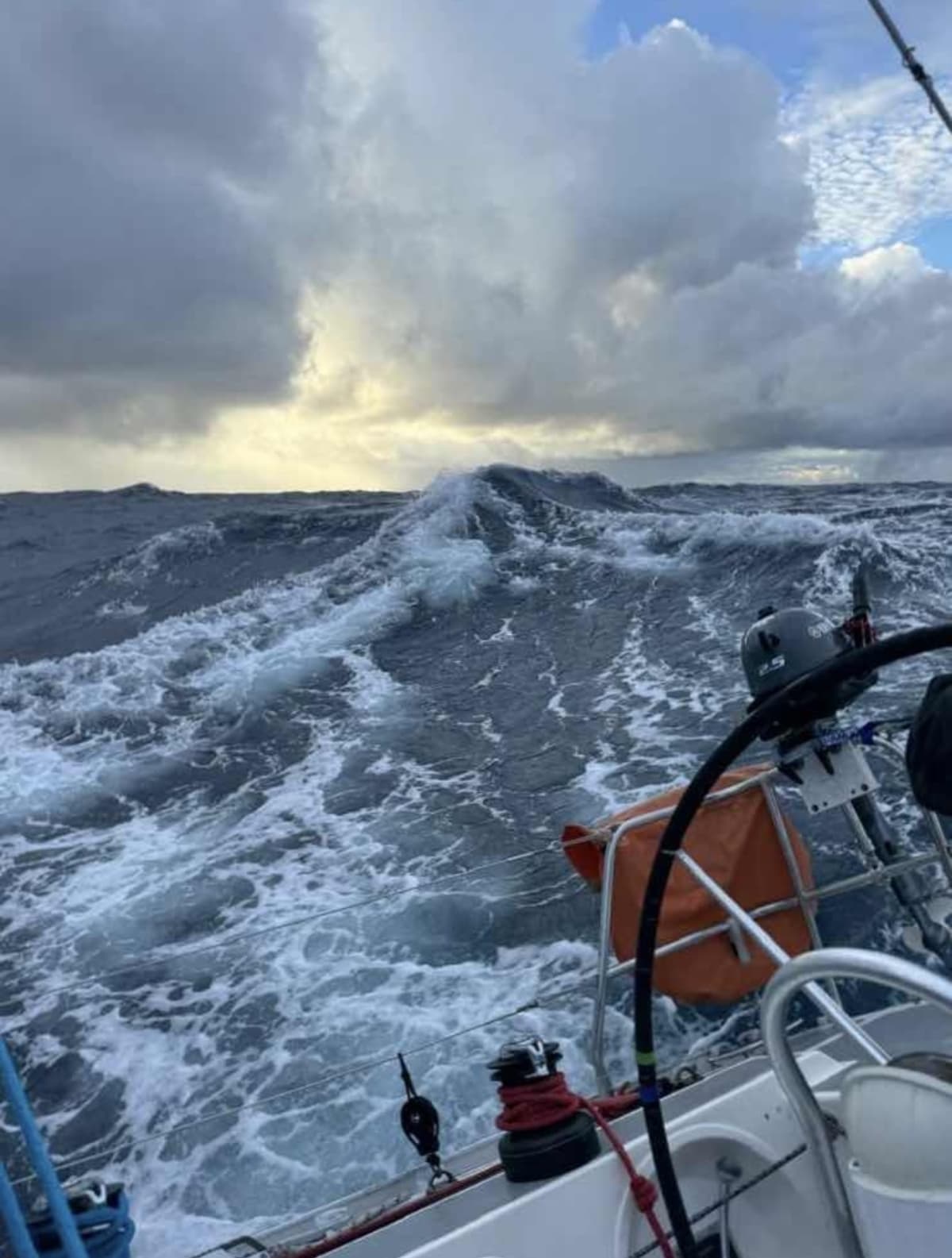 View from a sailboat cutting through rough ocean waves under stormy skies.