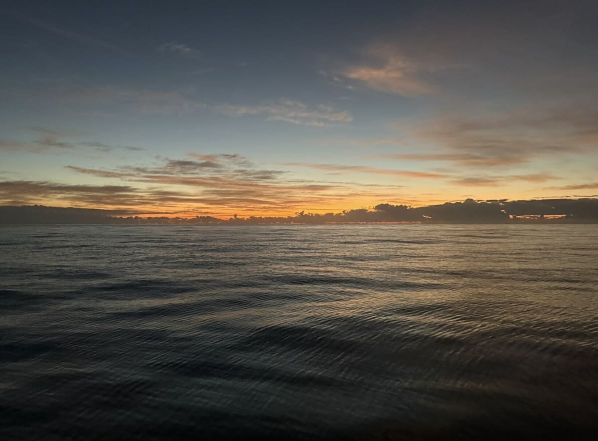Peaceful open sea with gentle ripples during a colourful evening sunset.