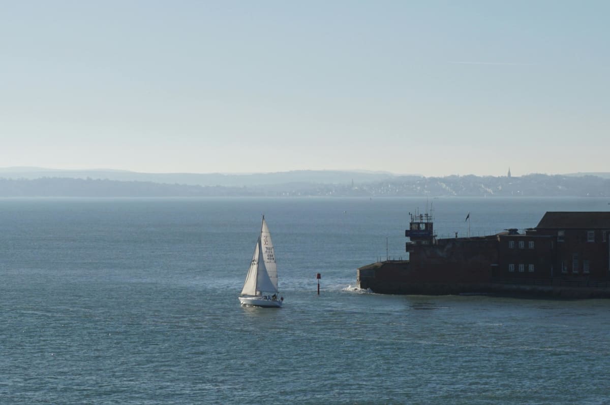 Sailboat cruising on calm open water with full sails under clear skies