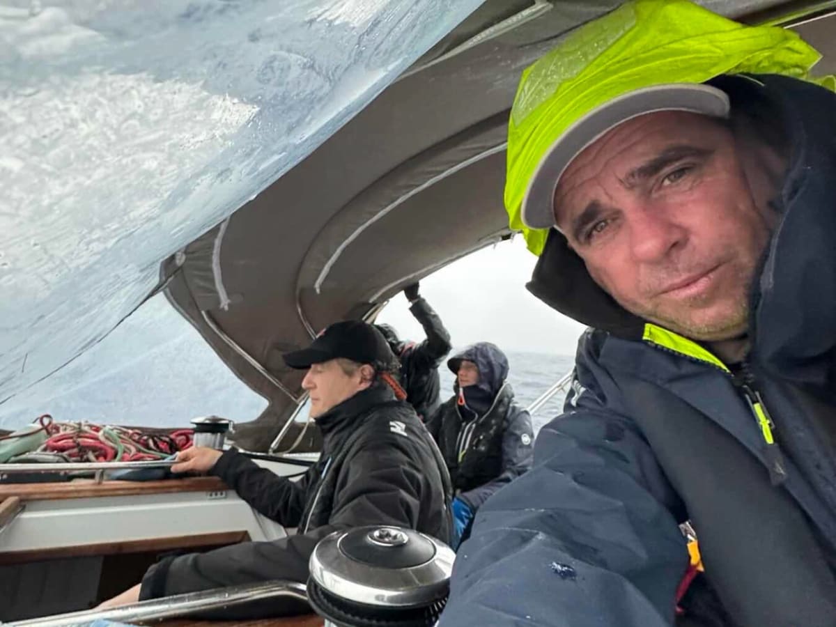Crew sailing in wet weather under cockpit cover