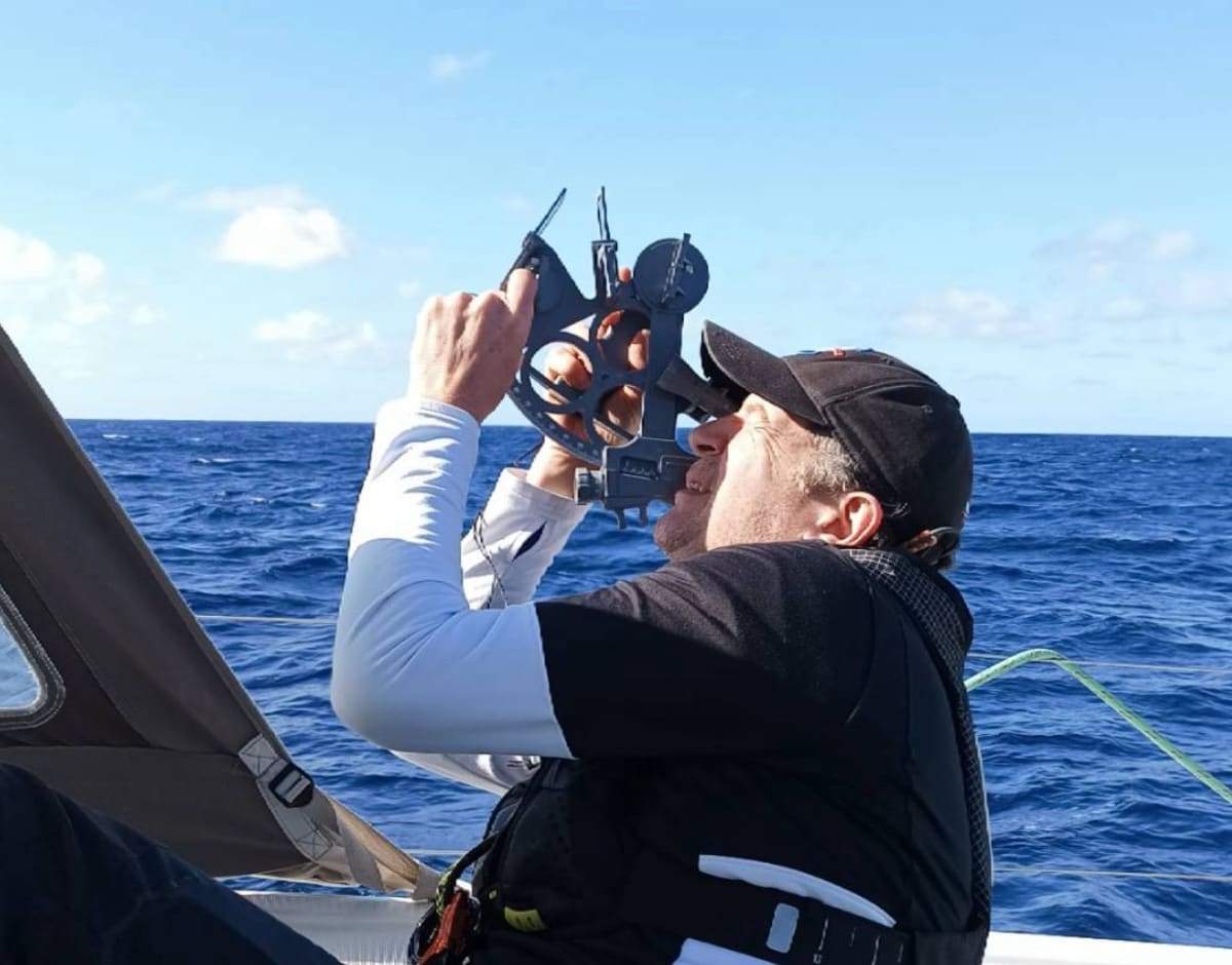 Sailor using sextant for celestial navigation at sea