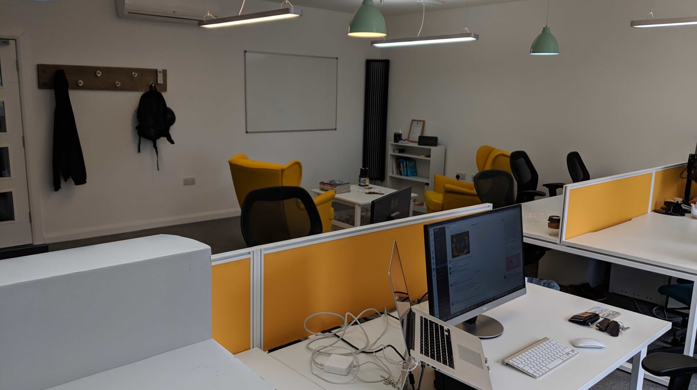The BuddieUp studio showing desks and monitors with yellow accents.