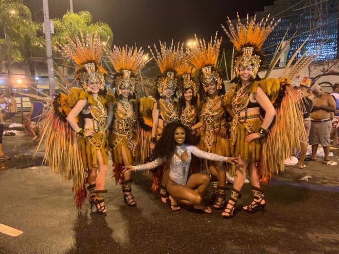 Dancers in elaborate costumes with feathered headpieces pose in Rio de Janeiro