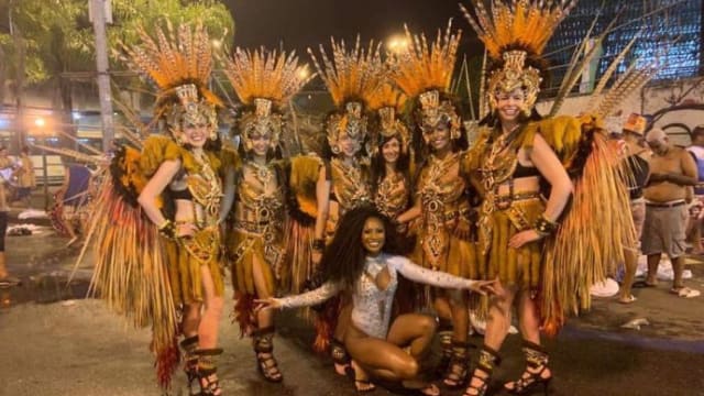 Dancers in elaborate costumes with feathered headpieces pose in Rio de Janeiro