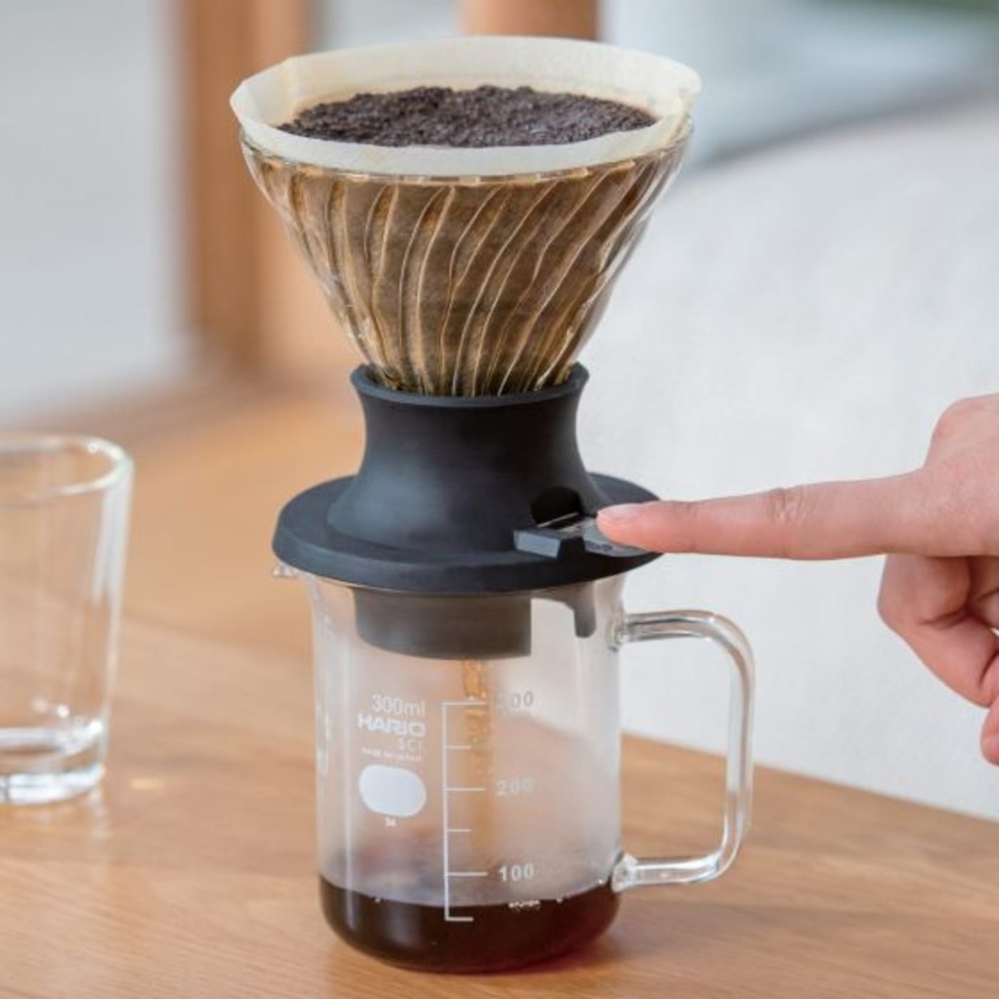 A Hario immersion dripper in use, activating the switch so the brewed coffee comes through.