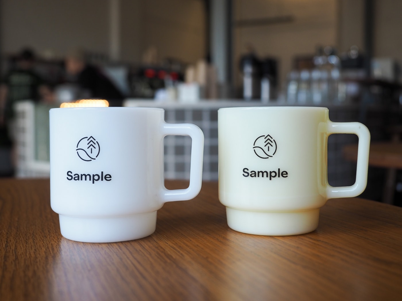 A pair of Sample Coffee x Jim Pluk mugs, view from the front (so with the Sample Coffee logo).