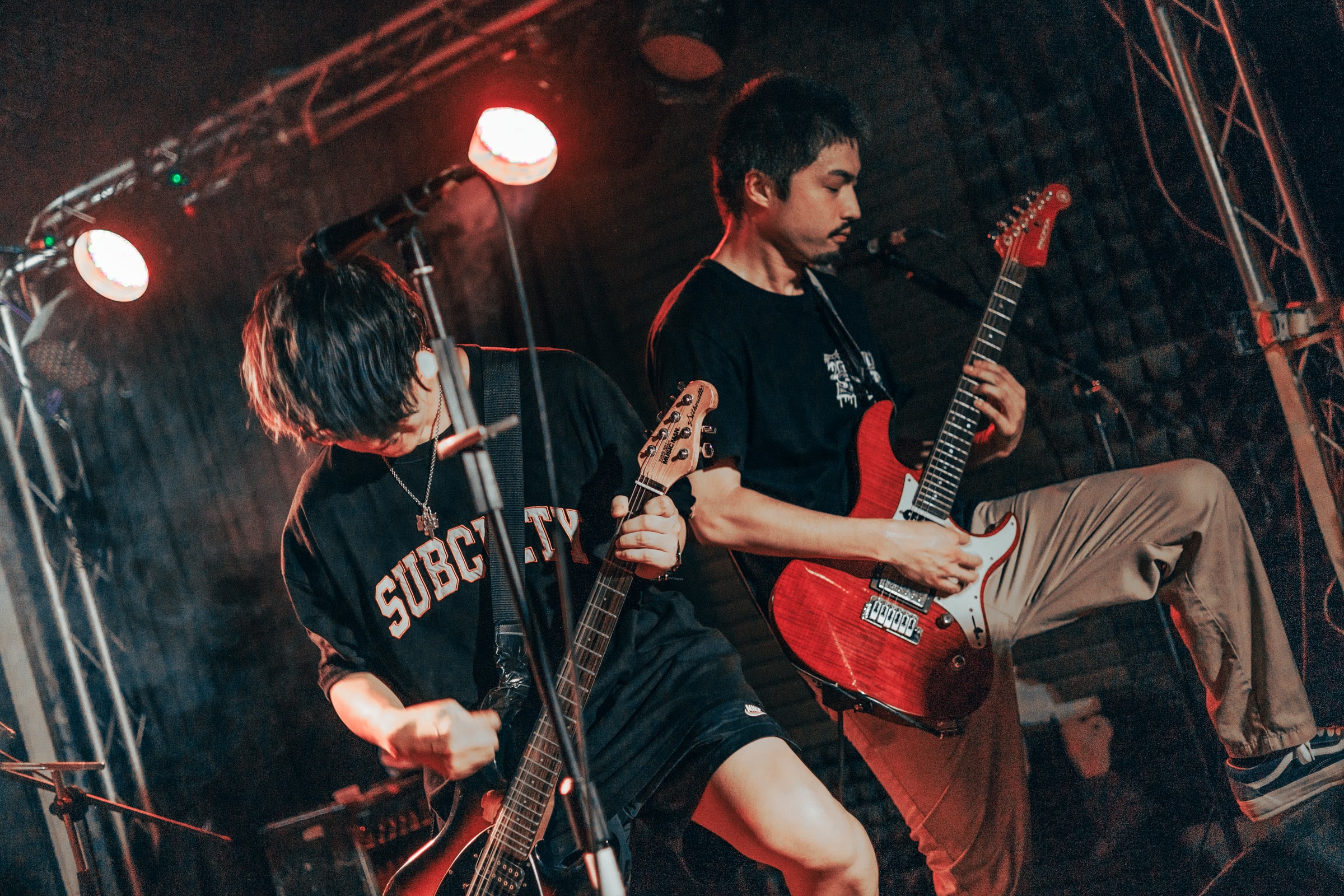 The Salitus的主唱以及吉他手在畫面中交錯站位，搭配黑與紅的舞台/燈光配色。