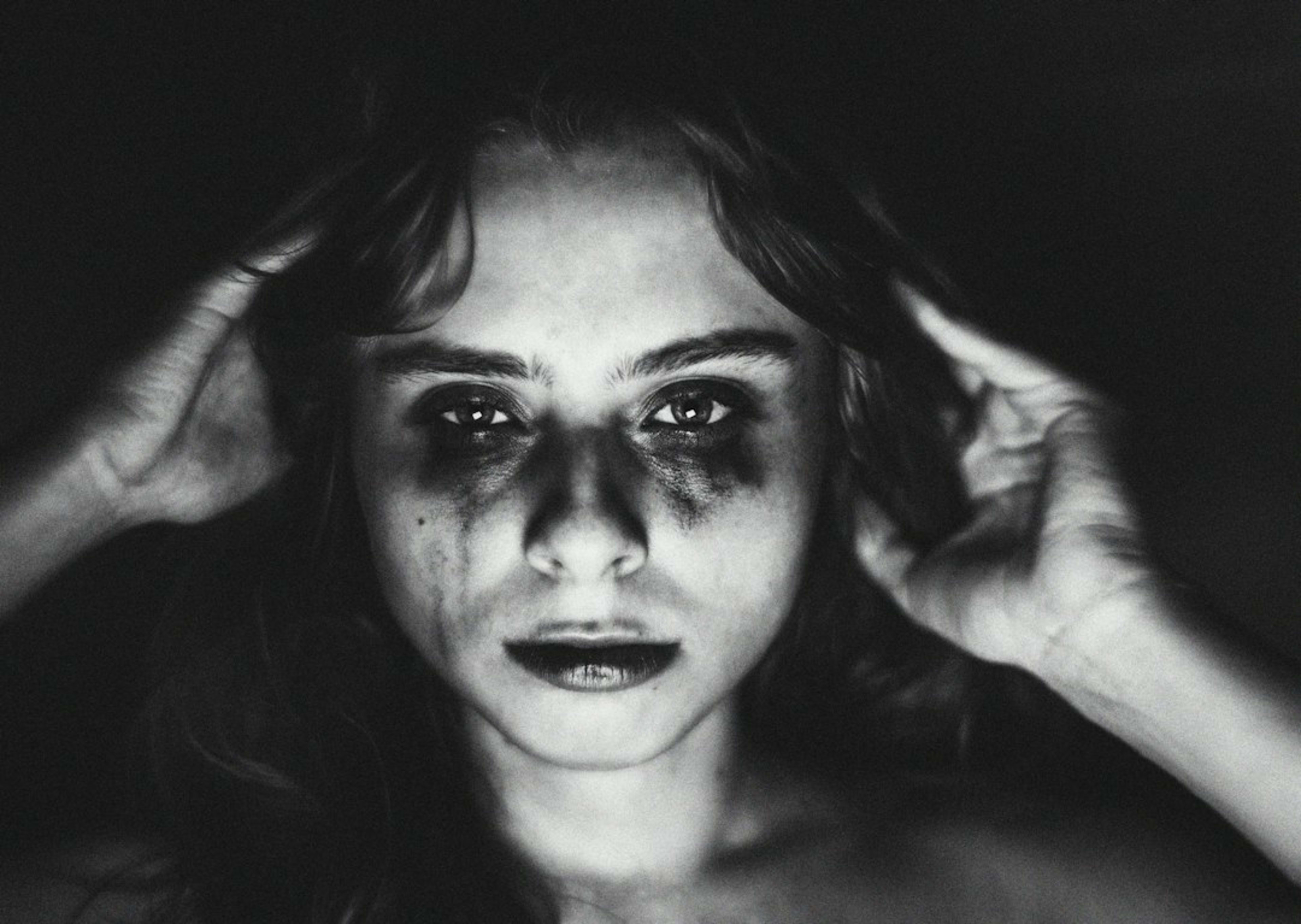 Woman with smudged makeup and distressed expression in darkness