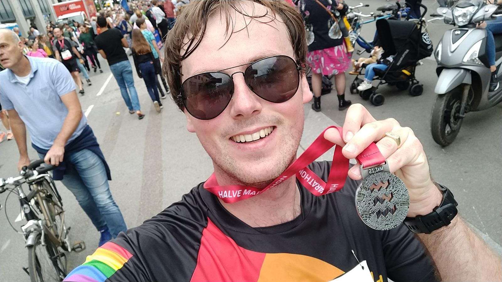 close-up van Sander Geraedts die zijn medaille voor de Halve Marathon van Eindhoven omhoog houdt