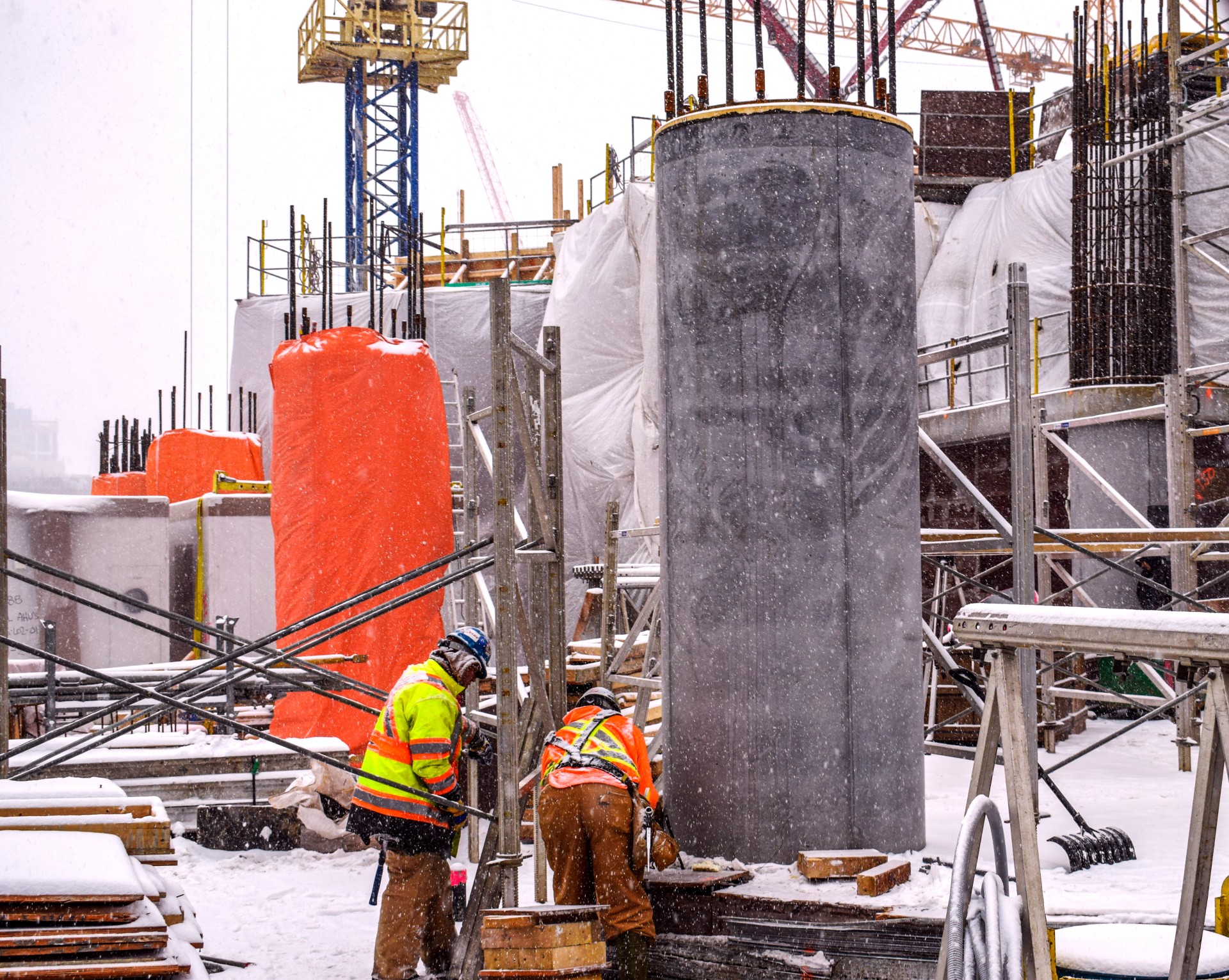 Construction site in Canada, it's very cold, it's snowing, the workers are checking the condition of the concrete. Canada, Toronto, Snow, Cold, Scaffolding