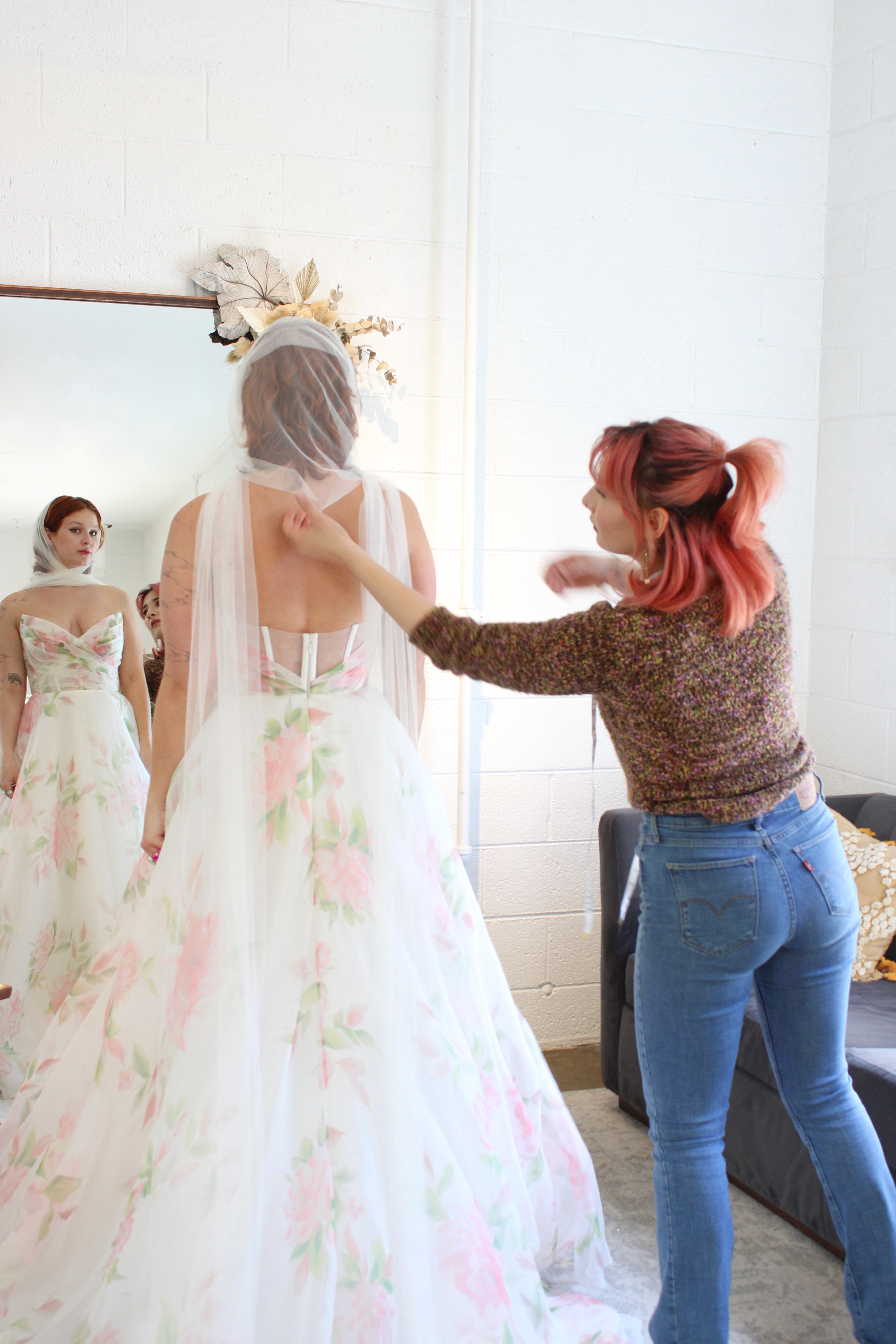 woman at a bridal salon looking into a mirror wearing a bridal scarf like a hood