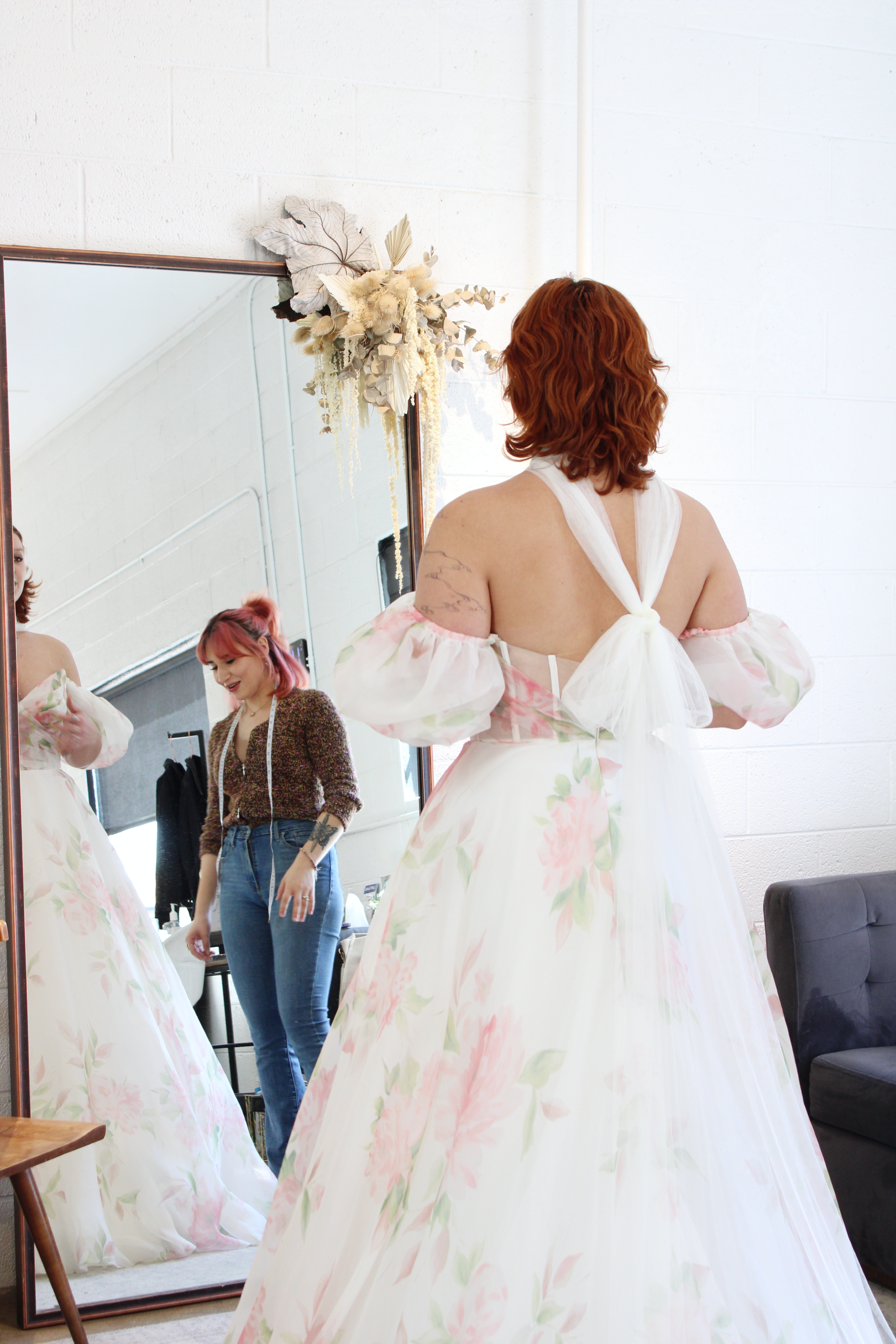woman at a bridal salon looking into a mirror wearing a bridal scarf tied into a bow