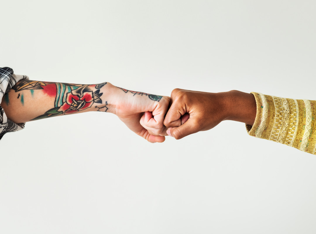 Two people bumping their fists together against a white background