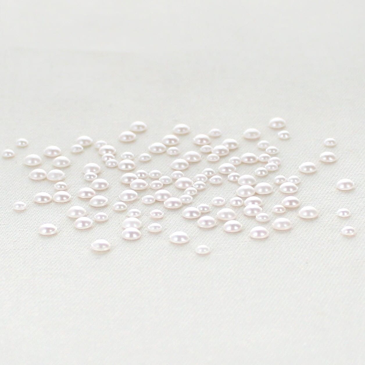off white flat pearls in multiple sizes sitting on a table