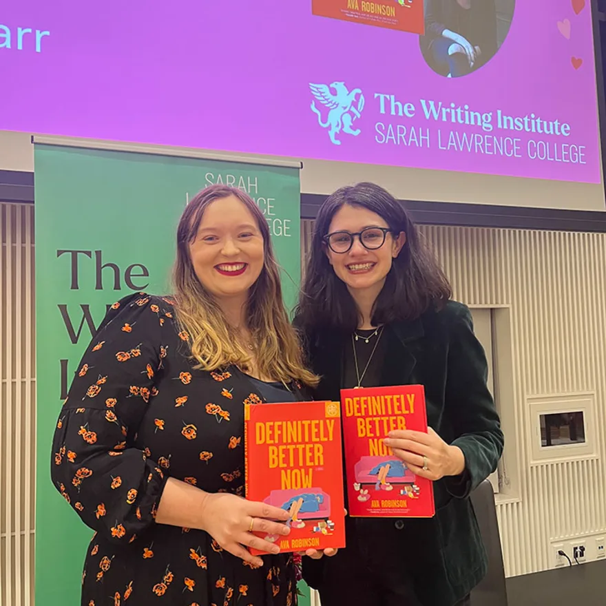 Two people smiling, holding books titled "Definitely Better Now" at a Sarah Lawrence College event.
