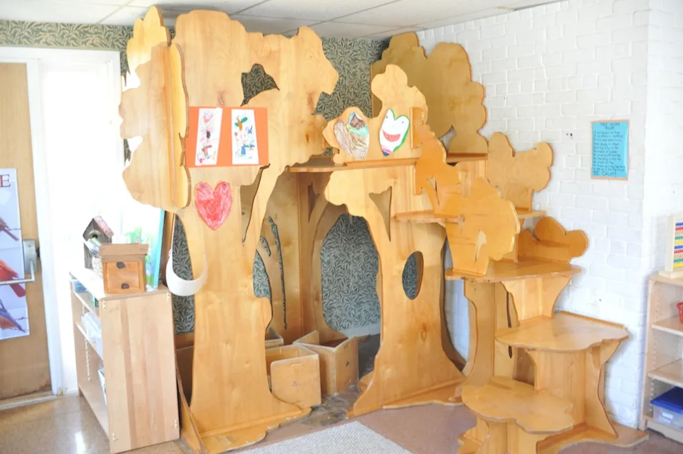 Wooden play structure with artistic cutouts and drawings displayed in a room.