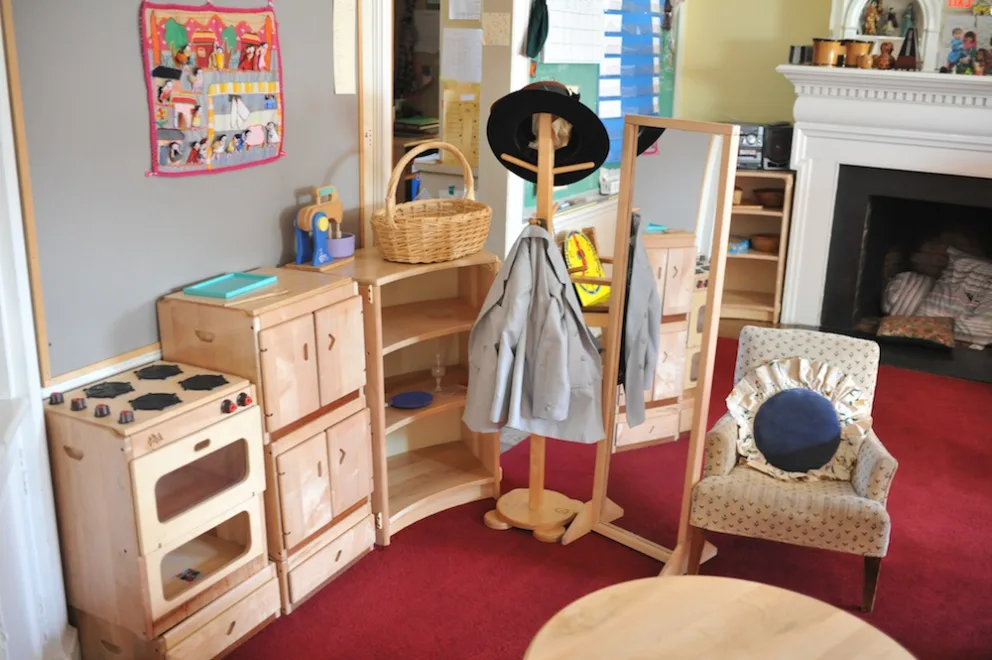 A cozy room with wooden children's furniture, a coat rack, and a small armchair.