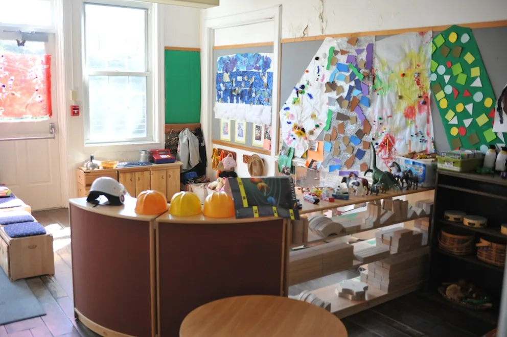 Colorful classroom with art projects, toys, and safety helmets.