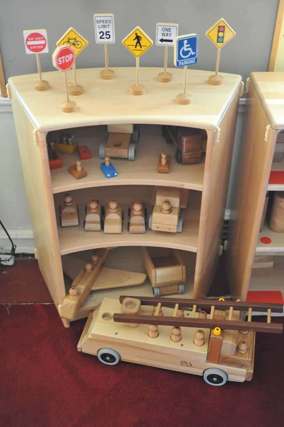 Wooden toy garage with cars and traffic signs.