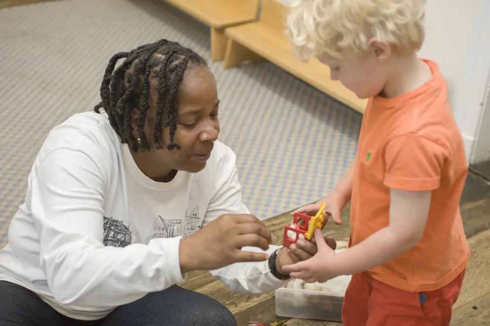 Adult and child playing with a toy together indoors.