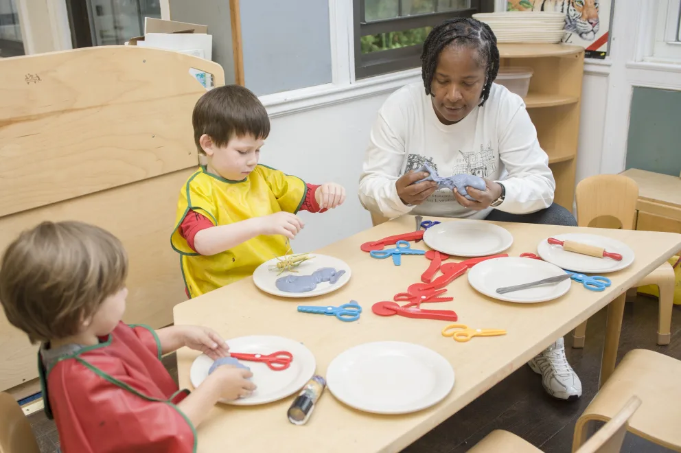 Two children and an adult at a table with plates and utensils.