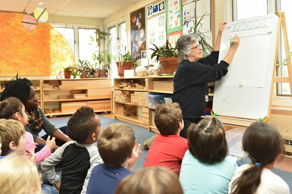 Teacher at whiteboard with attentive students in a classroom setting.