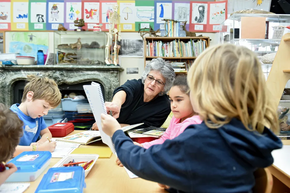 Teacher engaging with young students in a colorful classroom.