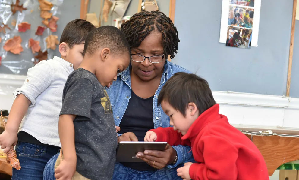 Adult and children looking at a tablet together.