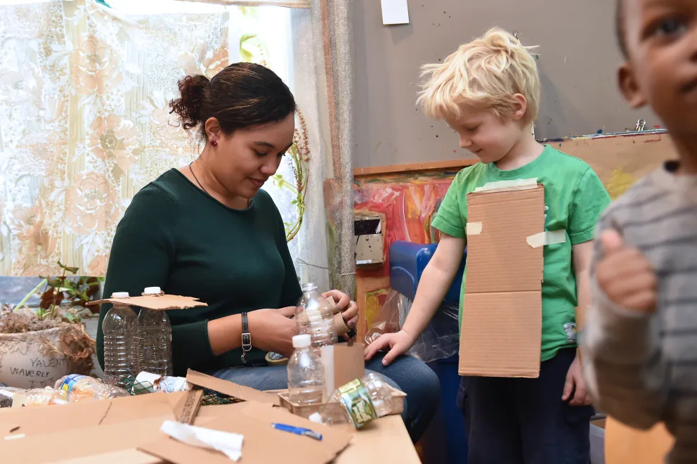 Adult teaching children about recycling with plastic bottles.