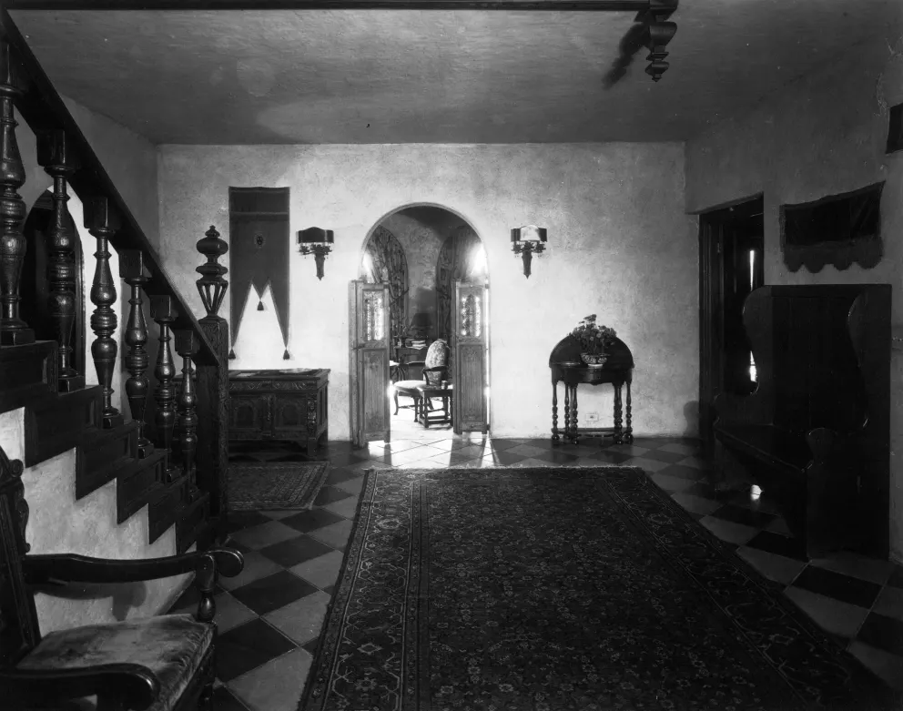 Interior of a vintage room with staircase, furniture, and patterned floor.