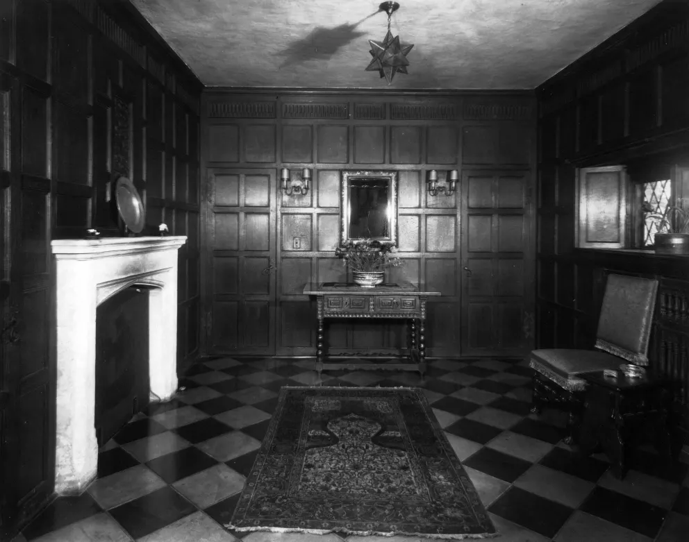 Vintage room with checkered floor, wooden paneling, fireplace, and decorative furniture.