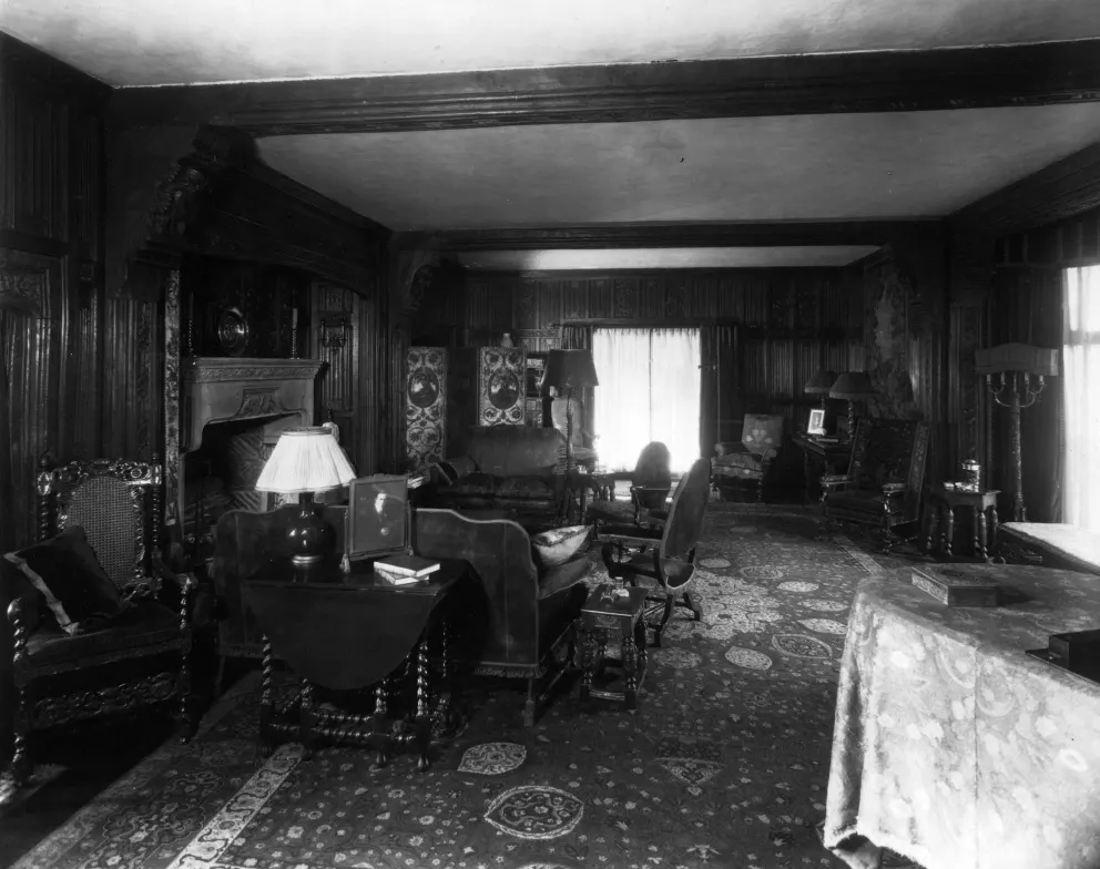 Vintage room with ornate wood paneling, furniture, and a fireplace.