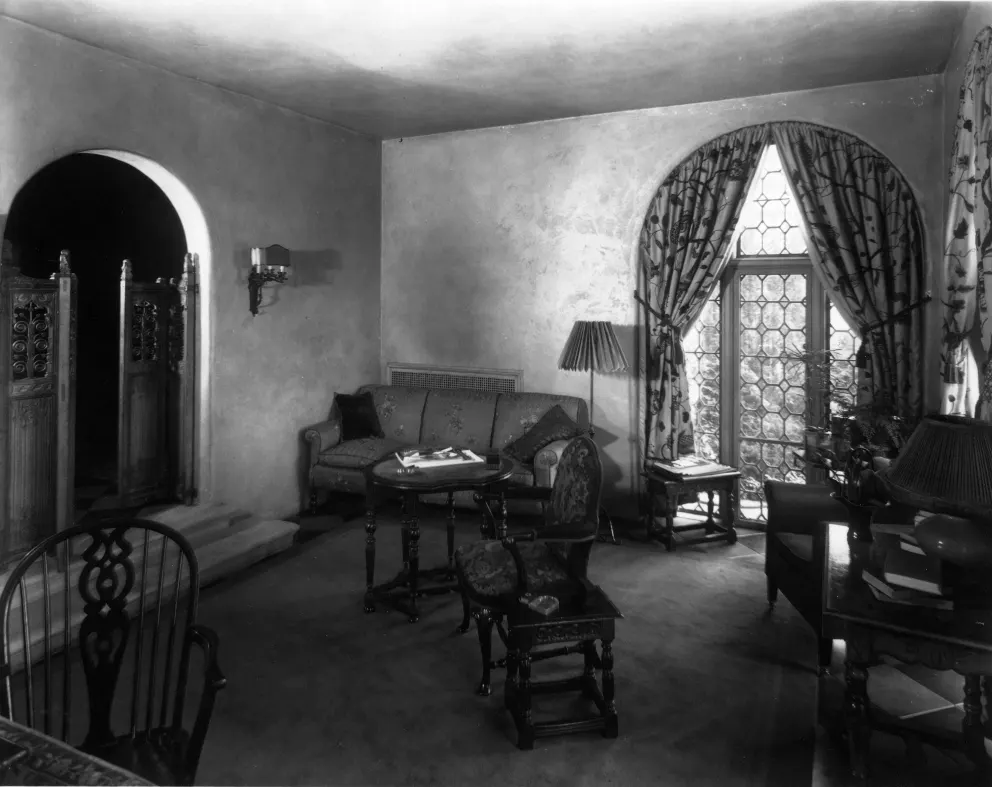 Vintage room with furniture, arched doorway, and patterned window curtains.