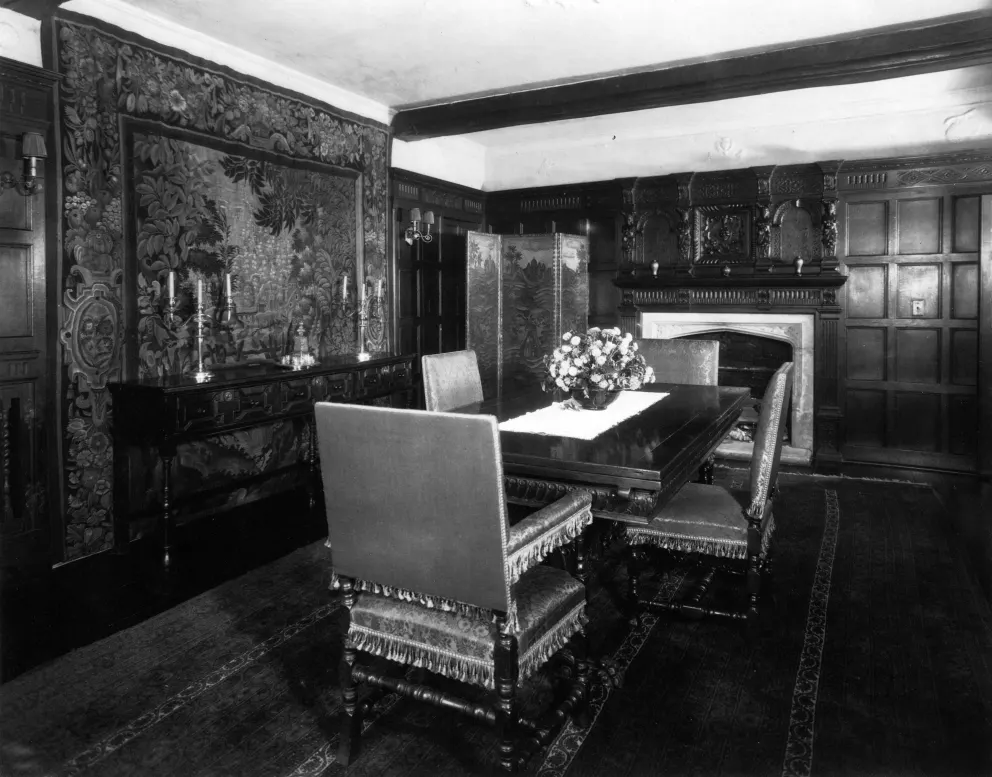 Vintage dining room with ornate furniture, a fireplace, and tapestry.