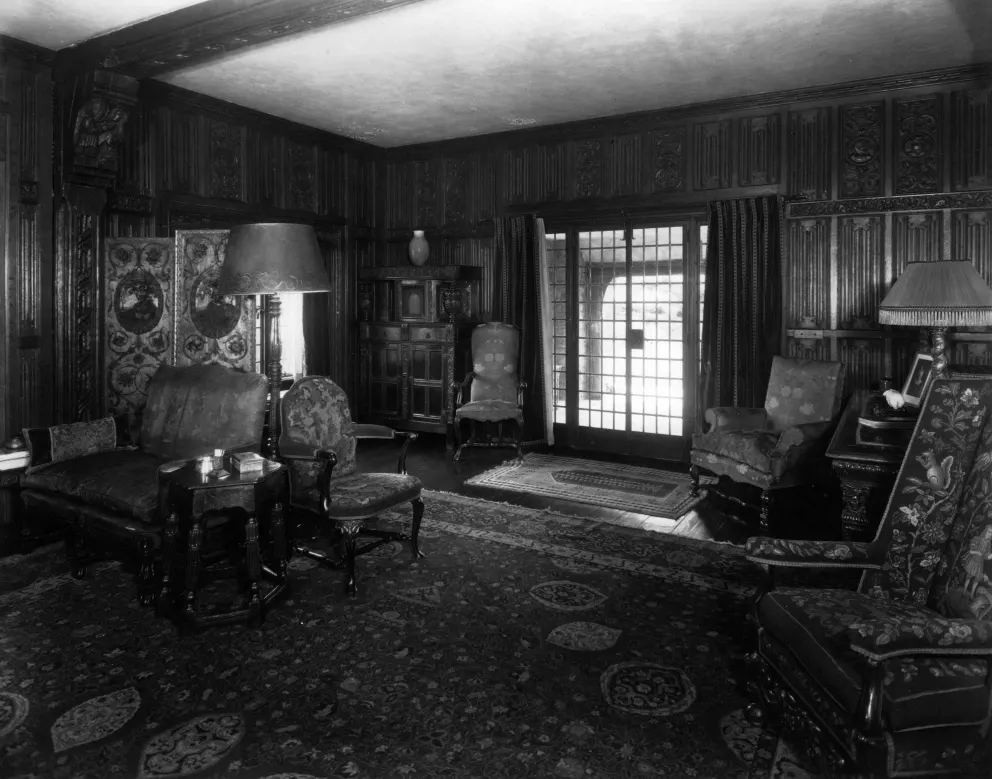 Vintage room with wooden paneling, ornate furniture, and patterned rugs.