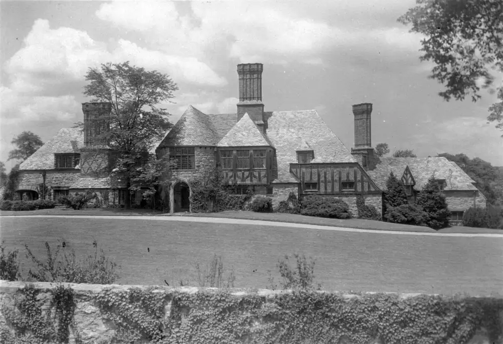 Vintage photo of a traditional stone house with multiple chimneys and a thatched roof.
