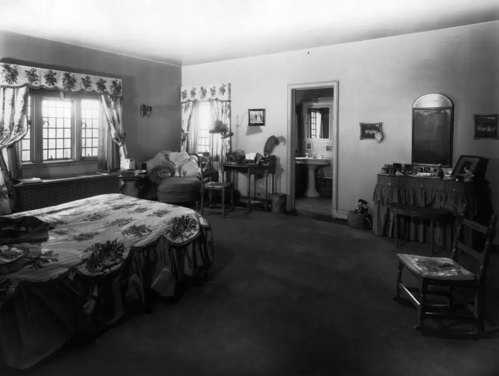 Vintage room with bed, desk, curtains, and decorative items.