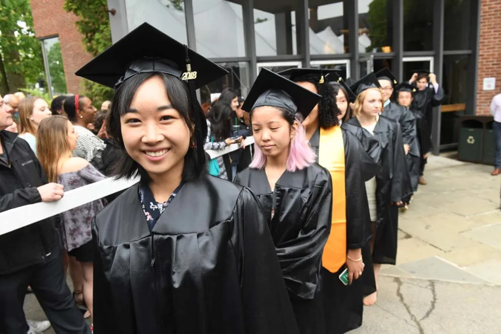Group of graduates in cap and gown smiling at a commencement ceremony.
