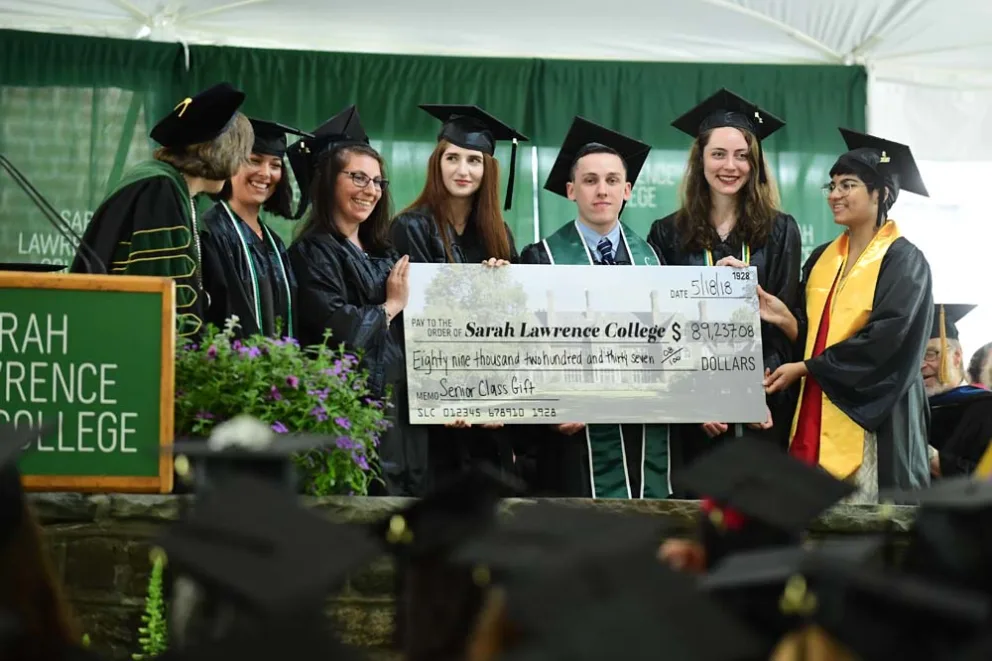 Graduates holding an oversized check at Sarah Lawrence College ceremony.