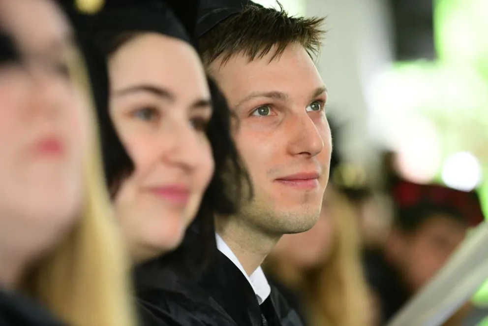 Graduates in caps and gowns attending a ceremony.
