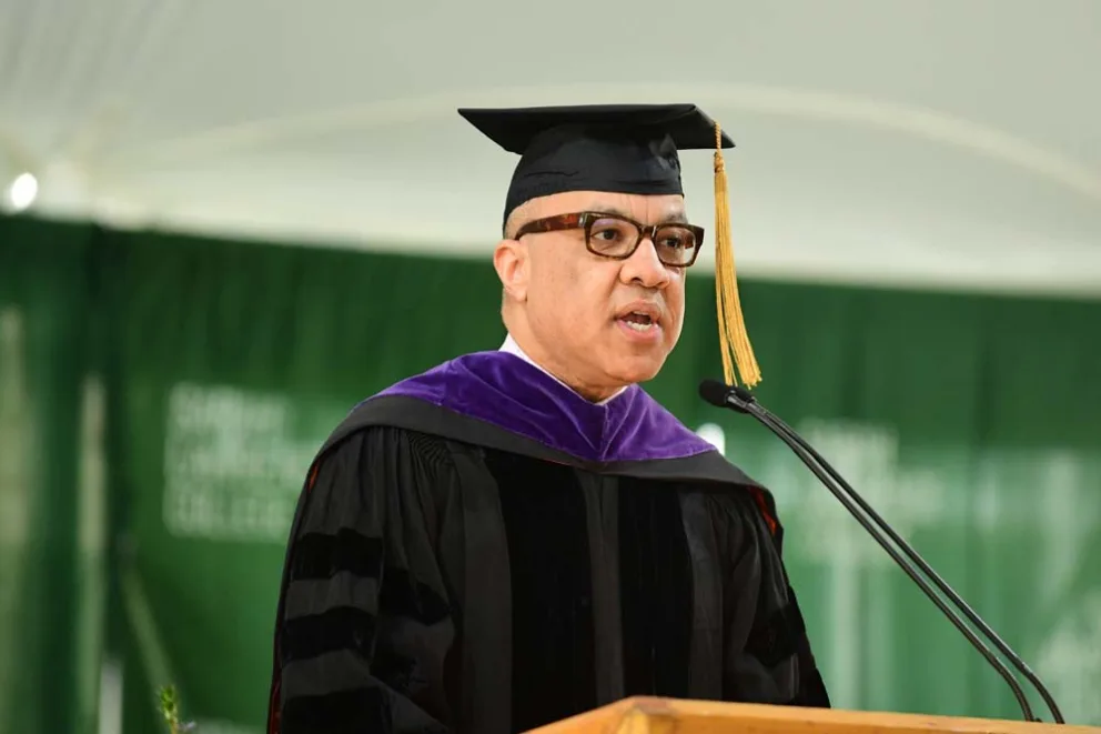 Person in academic regalia speaking at a podium.