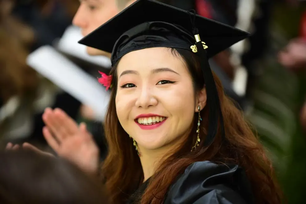 Graduate in cap smiling at a ceremony.